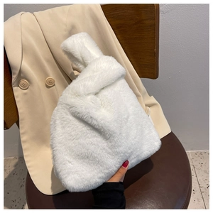 Detail of white faux fur handbag featuring a stylish knotted handle and soft texture