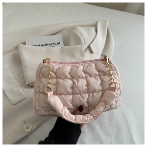 Detail showing pink quilted cloud bag with gold chain strap on a blazer background