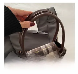 Dettaglio della borsa in lana a quadri marroni con doppie fibbie e finiture in pelle
