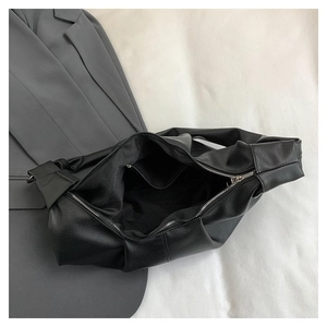 Detailed interior of black dumpling bag showing large capacity and zipper pocket