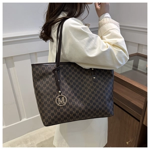 Close-up of monogram pattern tote bag with leather straps and gold metal M charm