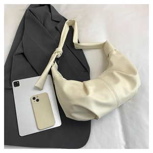 Detail of creamy white leather hobo bag with knotted shoulder strap and metal ring