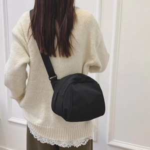Back view of a black canvas crossbody dumpling bag worn with adjustable wide strap