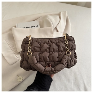 Detailed macro shot of brown quilted cloud bag with gold chain and satin texture finish