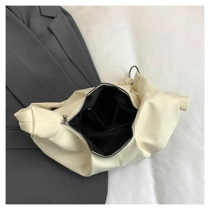 Detail view showing the spacious black fabric lining and inner pocket of a beige hobo bag