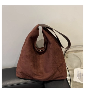 Close-up of brown suede tote bag featuring integrated wide shoulder strap and matte finish