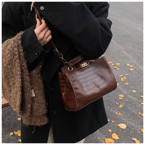 Détail du sac à main marron avec relief crocodile et fermoir rotatif en métal doré