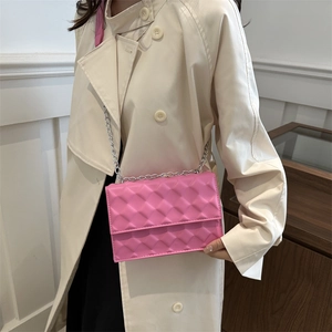 Chic quilted hot pink shoulder bag with silver chain strap on light beige trench coat