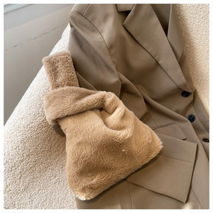 Detail of soft brown plush faux fur knot bag on aesthetic winter clothing background