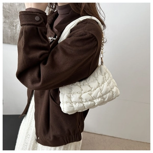 Close-up of white quilted cloud bag featuring a metal chain and puffy texture