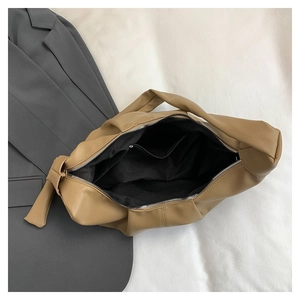 Detail view of large brown textured tote bag showing black fabric lining and inner zip pocket