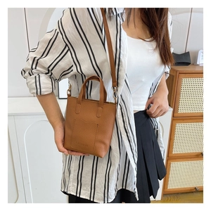 Detail of brown litchi pattern leather crossbody bag with Fashion embossed logo and strap