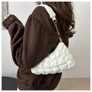 Detail of white quilted puffy shoulder bag with golden metal chain and soft fabric strap