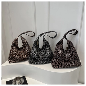 Close-up of three leopard print tote bags in brown, grey, and dark coffee on white pedestals