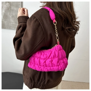 Detail of rose pink pleated cloud bag featuring soft quilted fabric and gold chain strap