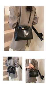 Détail de cuir noir texture crocodile avec fermoir rotatif doré sur le sac à main