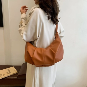 Detail of caramel brown leather pleated bag with knotted strap and lychee grain texture