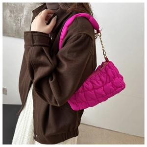 Close-up of bright pink quilted bubble underarm bag with gold metal chain and shoulder strap