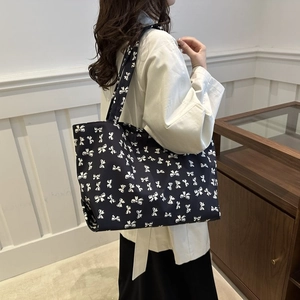 Navy blue tote bag with white bow pattern and wide shoulder strap for women