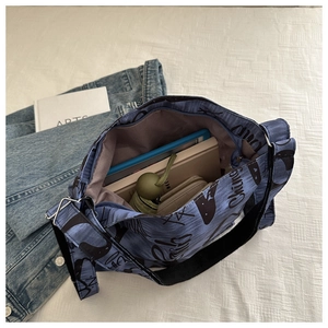 Detail of blue canvas tote bag interior with books and umbrella showing large capacity