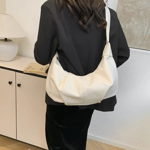 Close-up of pleated soft cream crescent bag featuring premium lychee texture leather