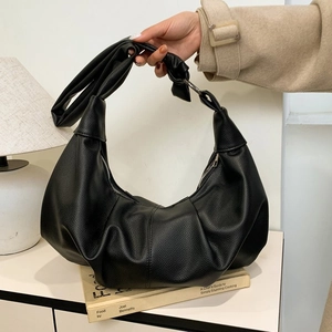Close-up of black lychee texture dumpling bag featuring silver metal ring buckle detail