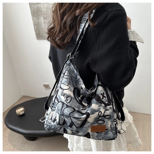 Detail of graffiti canvas crossbody bag showing spacious interior and leather logo patch