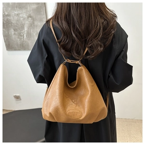 Close-up of mustard yellow vintage tote bag made of soft pleated leather with brand logo
