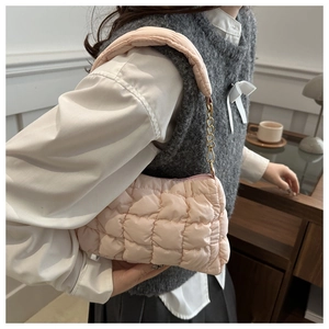 Detail of light pink quilted cloud bag with puffy texture and gold chain strap accent