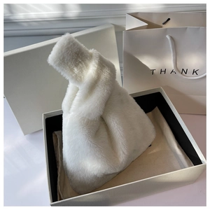 Detail of white faux fur handbag with knotted handle in elegant gift box