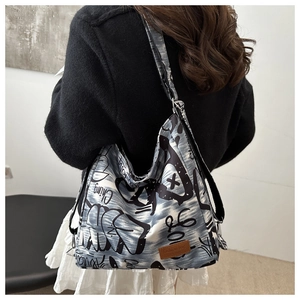Detailed back view of a blue canvas tote bag with black graffiti art and brown leather patch