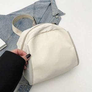 Detail of minimalist cream canvas crossbody bag with thick strap on a denim jacket