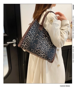 Detail of a large leopard print tote bag styled with a beige trench coat for a trendy look