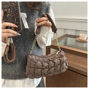 Detail of dark brown quilted bubble bag with metallic chain and soft textured fabric
