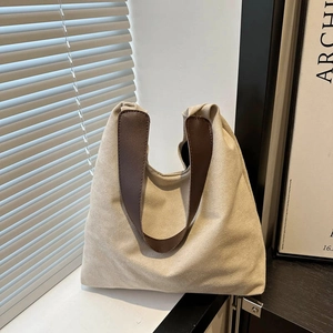 Minimalist beige suede tote bag with brown leather handles in a natural light setting