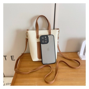 Mini tote bag in white and brown leather shown next to a smartphone for size reference
