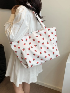 Détail du sac cabas en toile blanche avec imprimé fraise rouge sur un mannequin