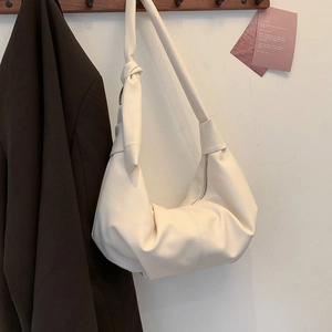 Detail of a beige pleated dumpling bag featuring a thick rope knot on the shoulder strap