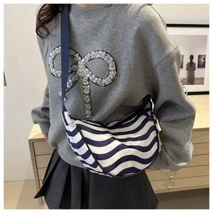 Borsa a tracolla a mezzaluna a righe blu e bianche indossata con un outfit casual grigio