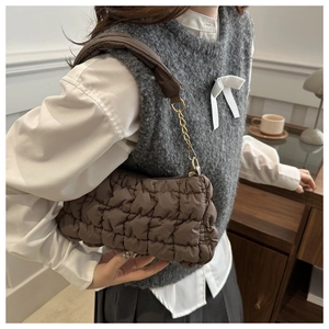Detail of brown quilted cloud bag featuring soft texture and gold chain fabric strap
