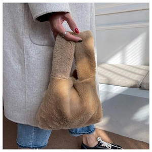 Detailed close-up of a plush camel brown faux fur handbag with a single strap handle