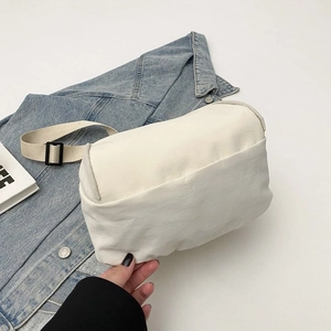 Detail of adjustable strap and matte black buckle on minimalist white canvas messenger bag