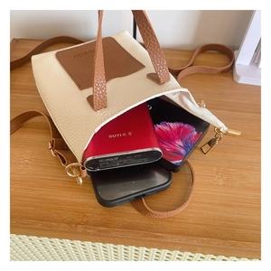 Detail view of contrast stitching handbag showing capacity for two phones and power bank