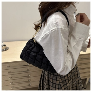 Close-up of black quilted bubble shoulder bag with elegant gold chain and zipper details
