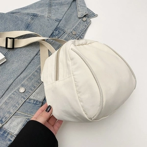 Detail of cream canvas crossbody bag shown next to a blue denim jacket for size context