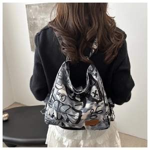 Detail showing graffiti print canvas backpack with leather patch and metallic D-ring