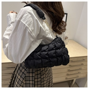 Detail of black quilted cloud bag with gold chain strap and soft pleated texture