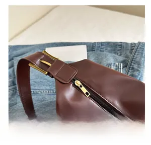 Detail of vintage brown leather tote showing smooth gold zipper and adjustable shoulder strap