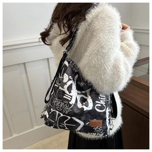 Detail of black tote bag with white street graffiti text and premium leather brand patch