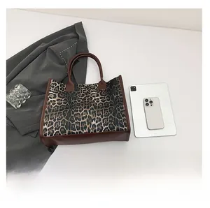 Detailed top view of a leopard print tote bag with brown leather base on a white surface